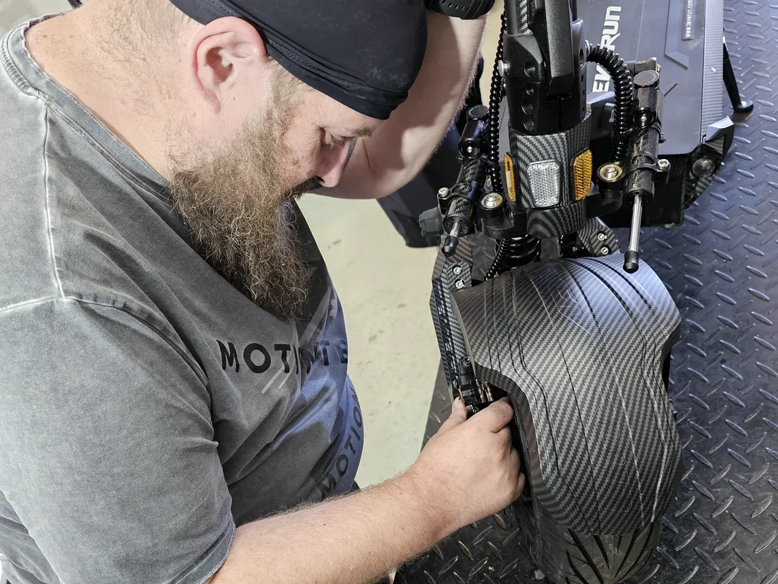 Techniker bei der Arbeit am Kotflügel und Hinterrad eines Scooters auf der Hebebühne